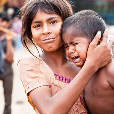 elder sister consoling crying younger brother,  rural India, at cattle fair in Pushkar, Rajasthan